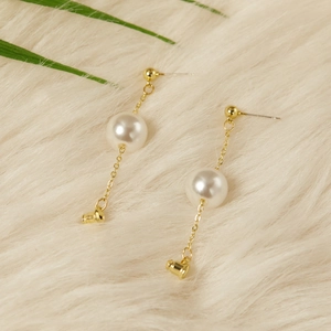 Elegant gold chain earrings with round white pearls on a soft white plush backdrop