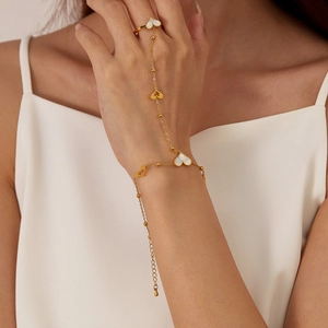 Golden stainless steel hand chain ring with mother of pearl hearts on a woman's hand