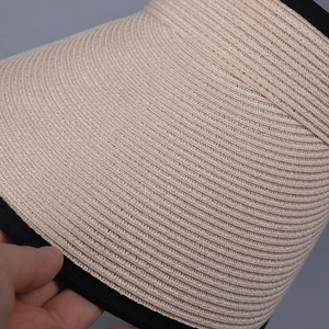 Close-up of khaki linen sun visor showing fine spiral weave and black ribbon edge