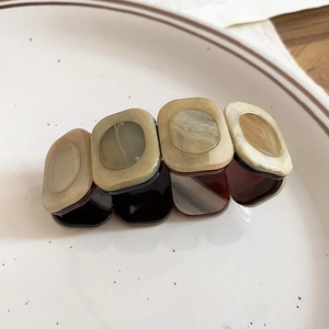 Close-up of a tortoise shell resin hair claw clip in brown and cream marble pattern