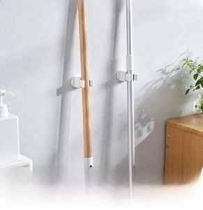 Close-up of wall-mounted mop holder showing secure adhesive grip for broom handles