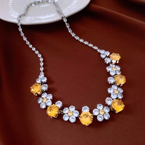 Detail of vintage silver necklace with yellow and clear zircon flower pendant on brown cloth