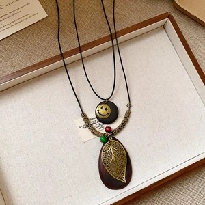 Detailed close-up of bohemian double-layer necklace with wooden leaf and smiley charms