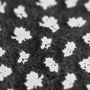 5D flower nail art stickers with delicate white daisy patterns on a dark plush background