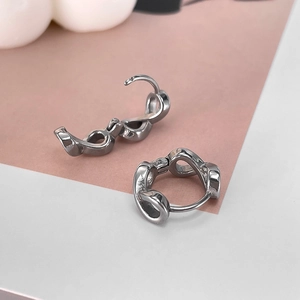 Close-up of silver chain twist earrings with hinge closure on soft pink background
