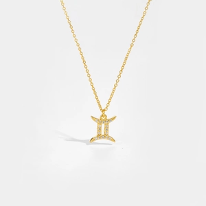 Detailed close-up of a gold Gemini pendant necklace with sparkling white zircons on white backdrop