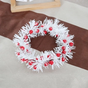 Detail of Christmas candle ring with white PVC pine needles and frosted red berries