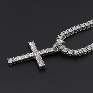 Macro view of silver tennis chain with cross pendant featuring sparkling clear cubic zirconia
