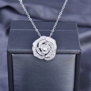 Macro shot of silver rose pendant with pavé diamonds on elegant dark silk fabric