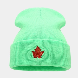 Close-up of mint green beanie with detailed red maple leaf embroidery on the cuff