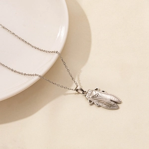 Macro detail of silver cicada pendant on a fine stainless steel chain necklace