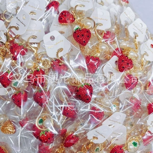 Detail of red strawberry keychain with rhinestones in individual packaging on display