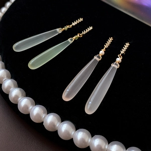 Detail of silver needle zircon drop earrings with translucent jade pendants on black velvet