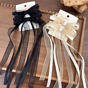 Detail view of lace bow hair clips with long tassels on display cards in a wooden tray