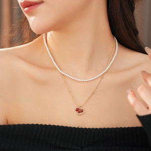 Close-up of elegant double-layered necklace with white pearls and red rocking horse pendant
