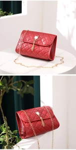 Close-up of red quilted bag with gold cat-head clasp and chain strap detail