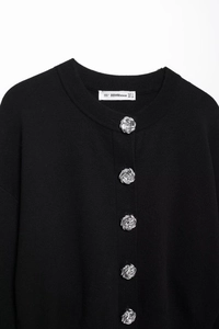 Detail of silver floral metal buttons and knit texture on this black cardigan jacket