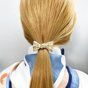 Minimalist gold alloy bow hair clip for elegant low ponytail styling on model