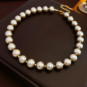 Close-up of champagne pearls with gold bead spacers on dark leather jewelry box