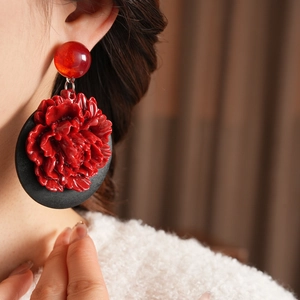 Gros plan de boucles d'oreilles fleur de pivoine en résine rouge portées sur un mannequin