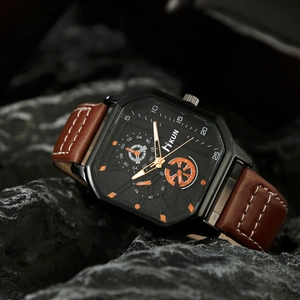 Detailed shot of large square quartz watch with brown leather strap on textured rock