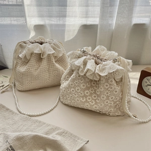 Detail von Spitzenbeuteltaschen mit Gänseblümchenstickerei, Rüschen und eleganten Perlenketten