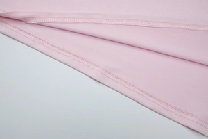 Detail of pink knitted fabric showing precision double-stitching and overlock seam work