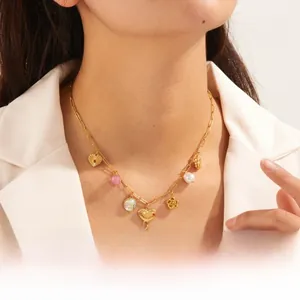 Detail shot of a gold-plated necklace with multiple heart and flower charms on a model