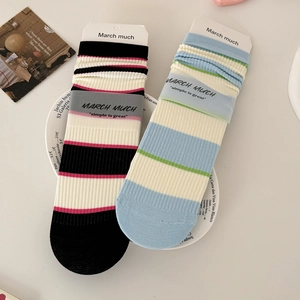 Striped cotton crew socks in pastel colors shown on a decorative ceramic display plate