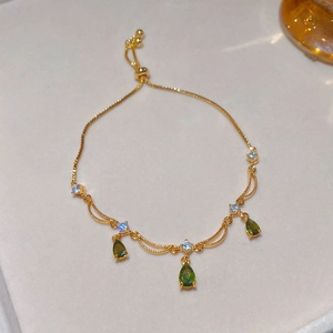 Dettaglio del bracciale regolabile dorato con pietre verdi a goccia e cristalli