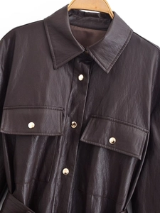 Detail of dark brown faux leather jacket texture with gold metal buttons and flap pockets