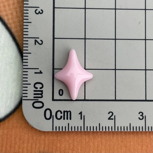 Close-up of a pink resin four-pointed star accessory on a measuring scale for size reference