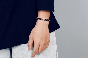 Close-up of black and silver stainless steel link chain bracelet worn on a male wrist