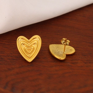 Polished 18K gold heart stud earrings with unique textured finish shown on white silk