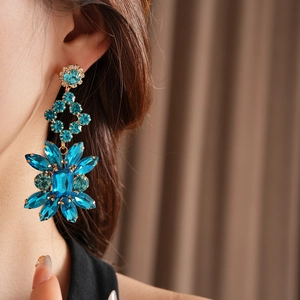 Gros plan sur des boucles d'oreilles fleur vintage avec cristaux bleus et or