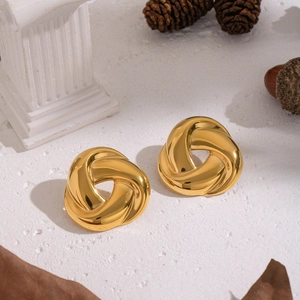 Golden geometric spiral triangle stud earrings in stainless steel on a white stone base