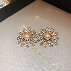 Detailed close-up of daisy stud earrings featuring orange pearls and white rhinestones