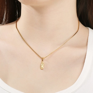Macro shot of gold Virgin Mary pendant on a box chain worn by a female model