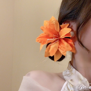 Detail of vibrant orange fabric lily hair clip with layered petals and realistic stamens