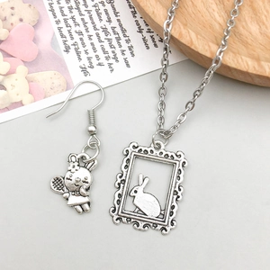 Close-up of vintage silver rabbit earrings and matching necklace pendant with detailed relief
