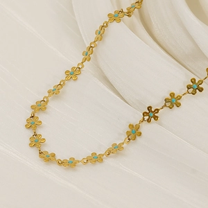 Collana in acciaio al titanio con fiori e pietre blu su sfondo di seta bianca