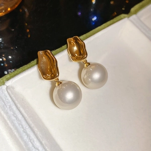 Detail showing French style gold hammered metal earrings with elegant white pearls