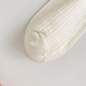 Macro shot of white waffle knit texture and stitching detail on breathable JK style socks