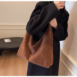 Detail of large brown suede tote bag texture shown against a black wool coat