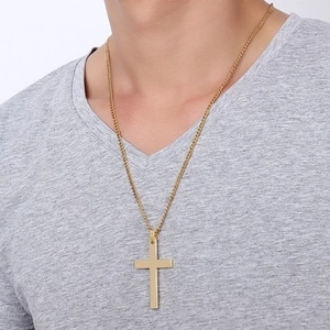 Polished gold cross pendant necklace for men worn by a model in a minimal style