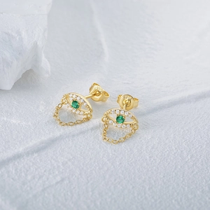 Macro detail of gold S925 silver evil eye earrings with green stone and chain tassel