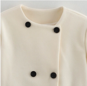 Detailed view of the crew neck collar and black contrast buttons on the cream wool coat