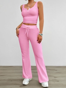 Detail of pink velvet yoga set featuring a buttoned V-neck top and drawstring flare pants