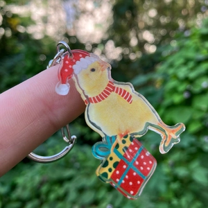 Detailed close-up of a Christmas chick acrylic keychain with gift boxes and a metal ring