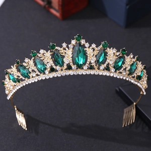 Close-up of golden bridal tiara with green emerald stones and crystal rhinestone details